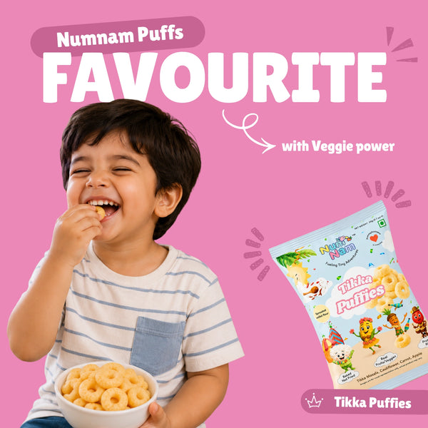 Happy toddler eating Tikka Puffies baked puff snacks with Num Nam Tikka Puffies bag and Numnam Puffs Favourite banner